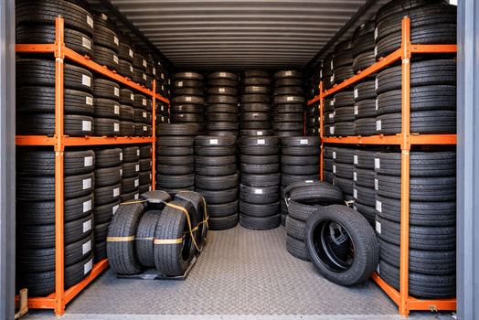 Georganiseerde bandenopslag met autobanden op metalen stellingen in een opslagruimte.