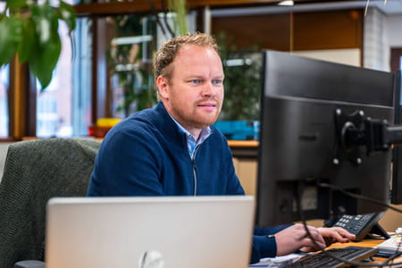 Medewerker berekent opslagprijs achter computer op kantoor.