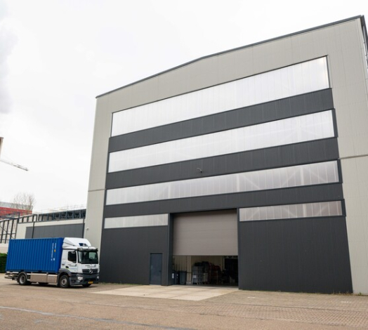 Bedrijfsgebouw van Slaop bij De Jong met opslag en vrachtwagen op het terrein.
