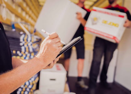 Medewerker maakt een inventarisatie tijdens een verhuizing terwijl verhuisdozen worden gecontroleerd.